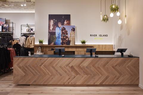 Interior of River Island Boutique in Porstmouth, showing wooden cash desk and posters